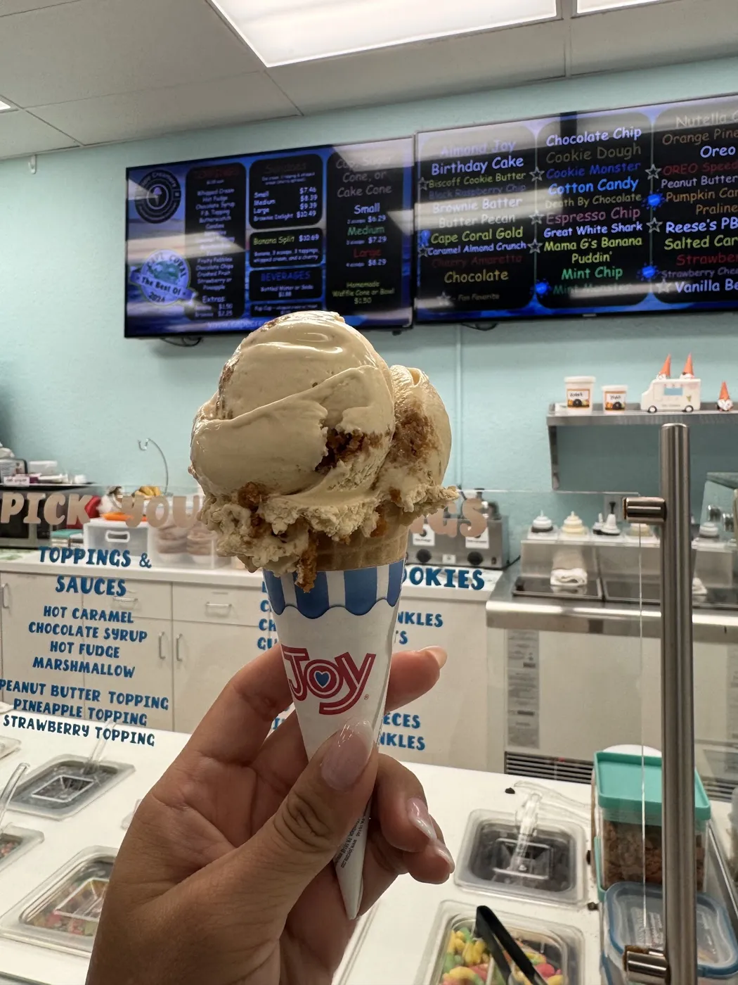 A hand holding an ice cream cone in the shop